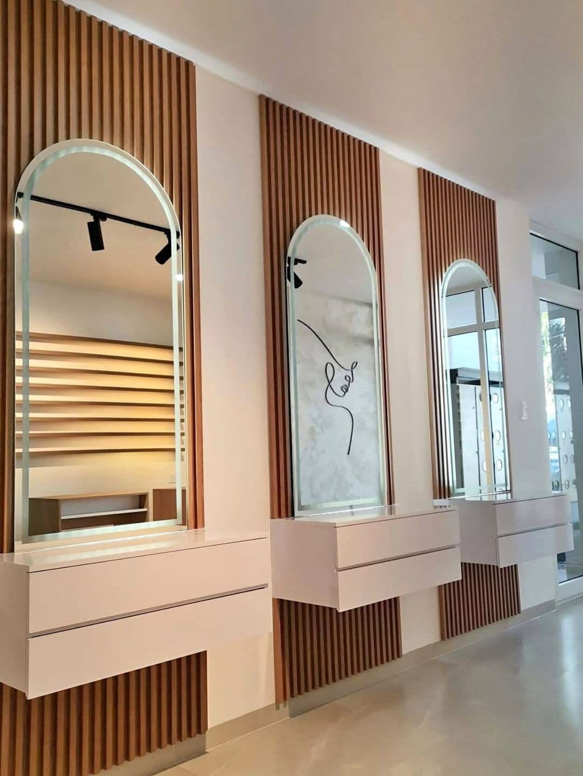 Arched vanity mirrors along a wood-slat wall